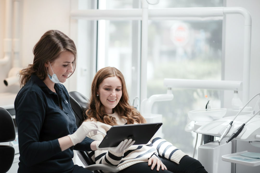 Implantoloog bespreekt samen met een patiënt het behandelplan voor een implantaat met behulp van digitale diagnostiek.